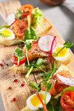 Smoked Salmon Bruschetta with Pita Bread, Quail Egg and Vegetables. Canape fish food appetizer on grey table with wooden board. Healthy, gourmet, appetizers food concept.