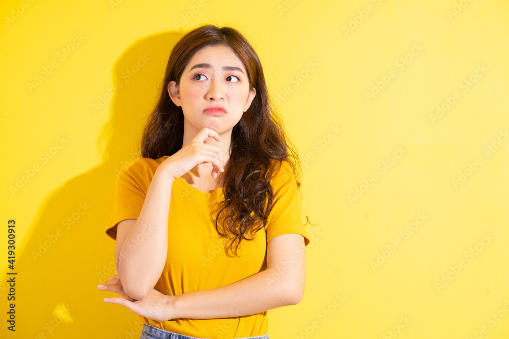 Young Asian girl posing on yellow background
