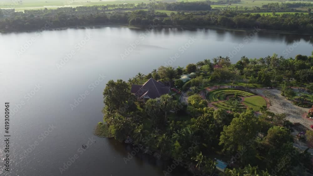View from drone flying over well-groomed park lake. Bright evening sunshine. Houses on the water. View from drone flying over well-groomed park lake. Bright evening sunshine. Houses on the water.