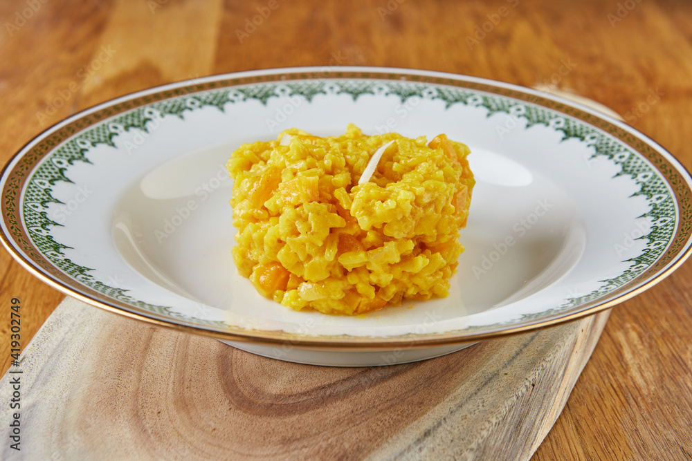 Risotto, ready-made portion of step-by-step recipe in a vintage plate on a wooden background Risotto, ready-made portion of step-by-step recipe in a vintage plate on a wooden background