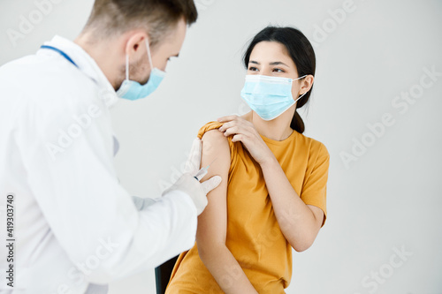 Canvas-taulu doctor injecting a woman in a yellow t-shirt in the shoulder close-up covid vacc