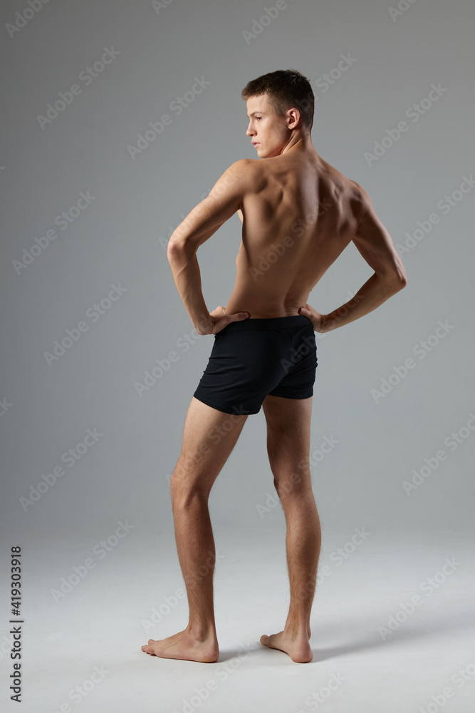 sporty man with pumped up body black shorts back view isolated background