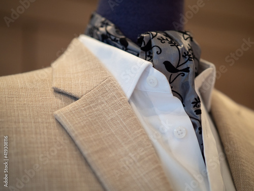 Bild auf Leinwand Close up of beige jacket suit with white shirt and ascot tie scarf on mannequin