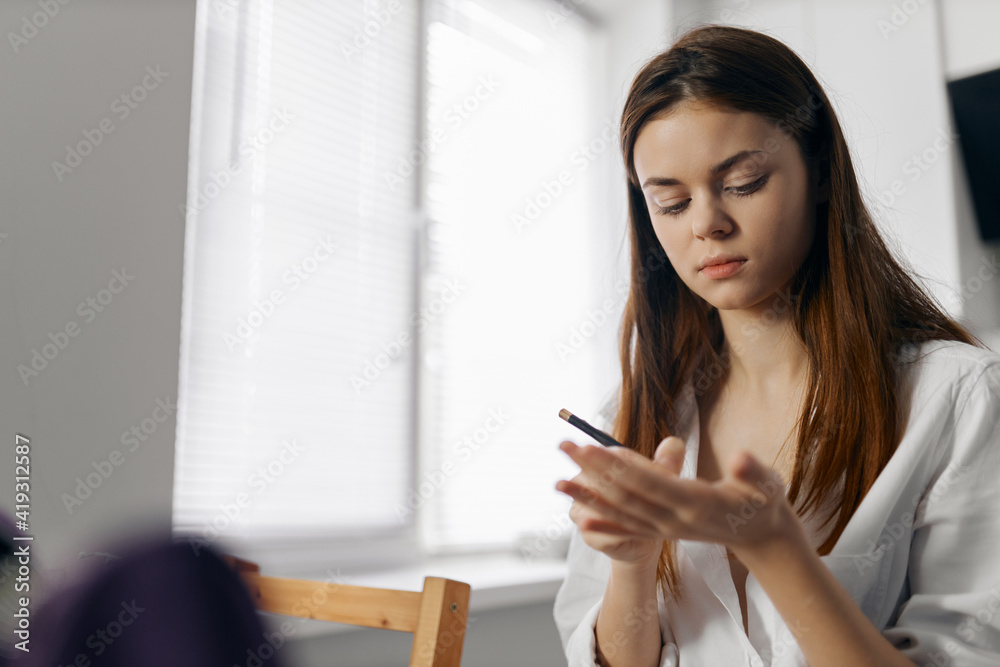 woman holding makeup pencil in hand indoors near window woman holding makeup pencil in hand indoors near window