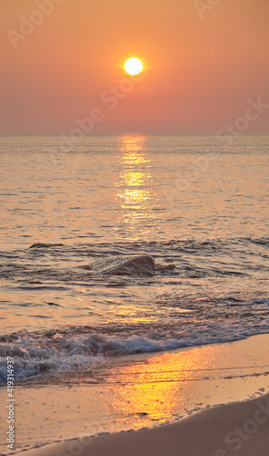 Golden sunset over sea, selective focus on rock.