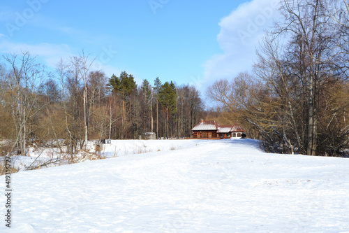 Old small wooden house in the winter forest in sunny weather