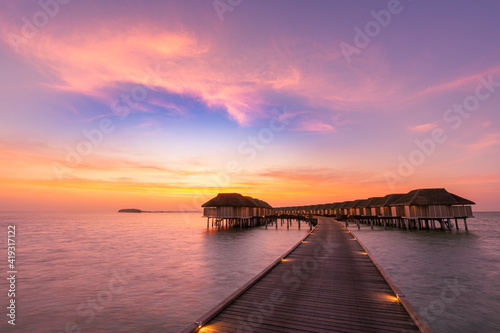 Amazing panoramic sunset Maldives. Luxury resort villas seascape with soft led lights under colorful sky. Beautiful twilight sky and colorful clouds. Beautiful beach background for vacation holiday