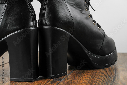 Woman high hills boot with lace on a wooden floor. High fashion industry. Leather stylish shoes