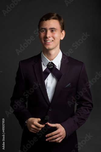 a young dark-haired man in a white shirt, dark purple suit and a ribbon male cross bow tie