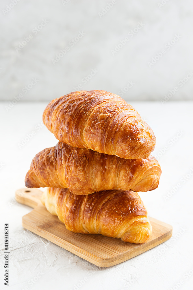 Croissants in a stack on a wooden board on a white background. Croissants in a stack on a wooden board on a white background.