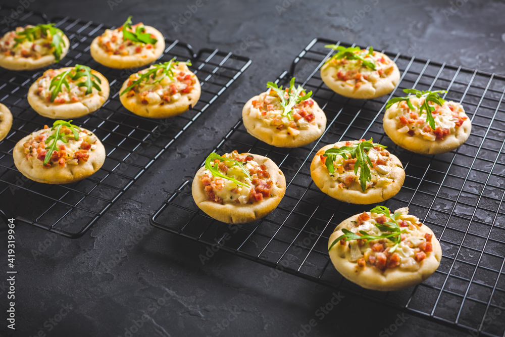 Small tarte flambee or mini pizza with onion, bacon and arugula Small tarte flambee or mini pizza with onion, bacon and arugula