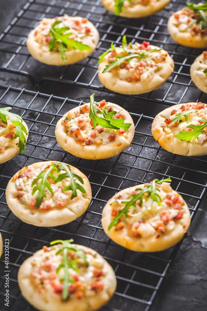 Small tarte flambee or mini pizza with onion, bacon and arugula Small tarte flambee or mini pizza with onion, bacon and arugula
