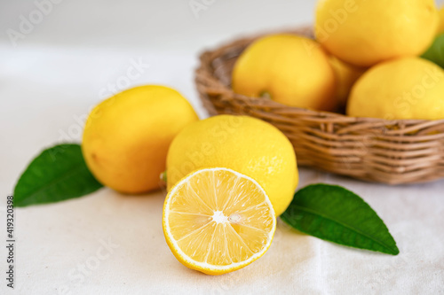 Group of whole and cut organic lemon in wood basket on white background. Fresh lemon have high vitamin C and delicious sour taste for lemonade or cooking. Citrus or citron fruit concept.
