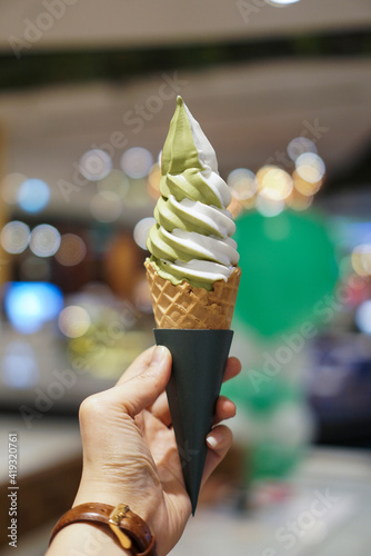 Matcha and vanilla soft serve ice cream. Woman holding a cone of ice cream.