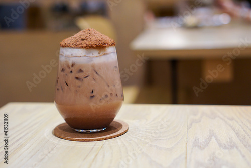 Iced Chocolate Bomb topped with cocoa powder likes volcano on wooden table in cafe. photo