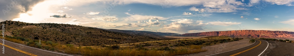 Panorama shot of road goes around colorado desert nature at sunsetting sky with clouds in america
