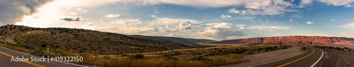 Panorama shot of road goes around colorado desert nature at sunsetting sky with clouds in america