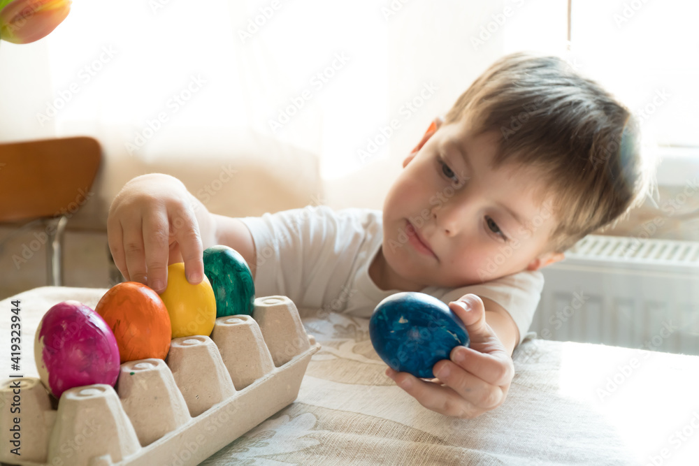 Fototapeta premium Little preschool boy play with colored egg in spring easter day indoors