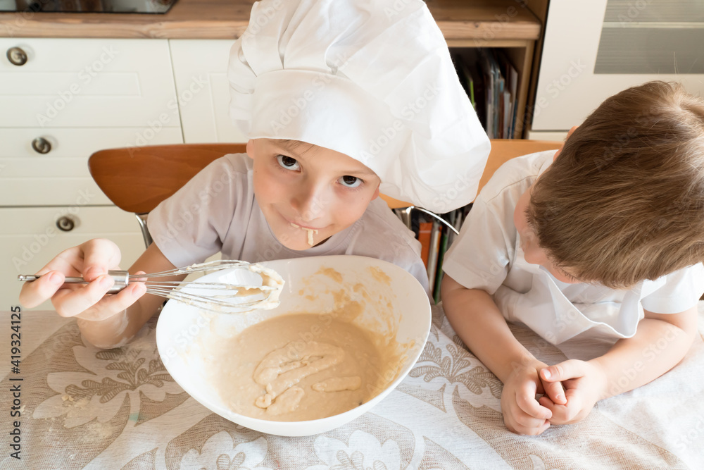 little child baking and tasting the dough in kitchen, shot from above