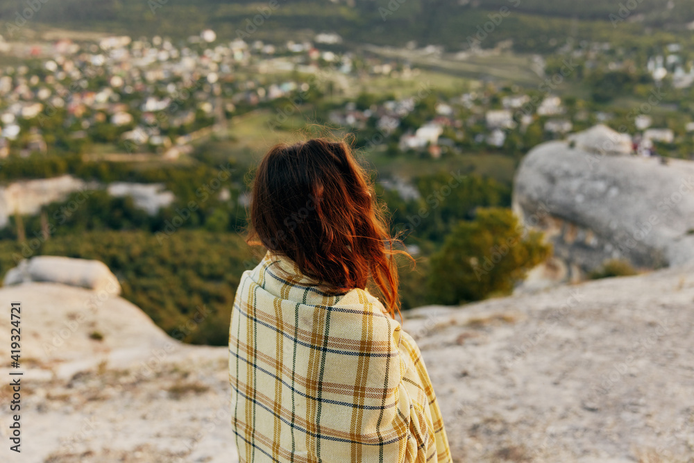 red-haired woman with a plaid on her shoulders looks at the village in the distance red-haired woman with a plaid on her shoulders looks at the village in the distance