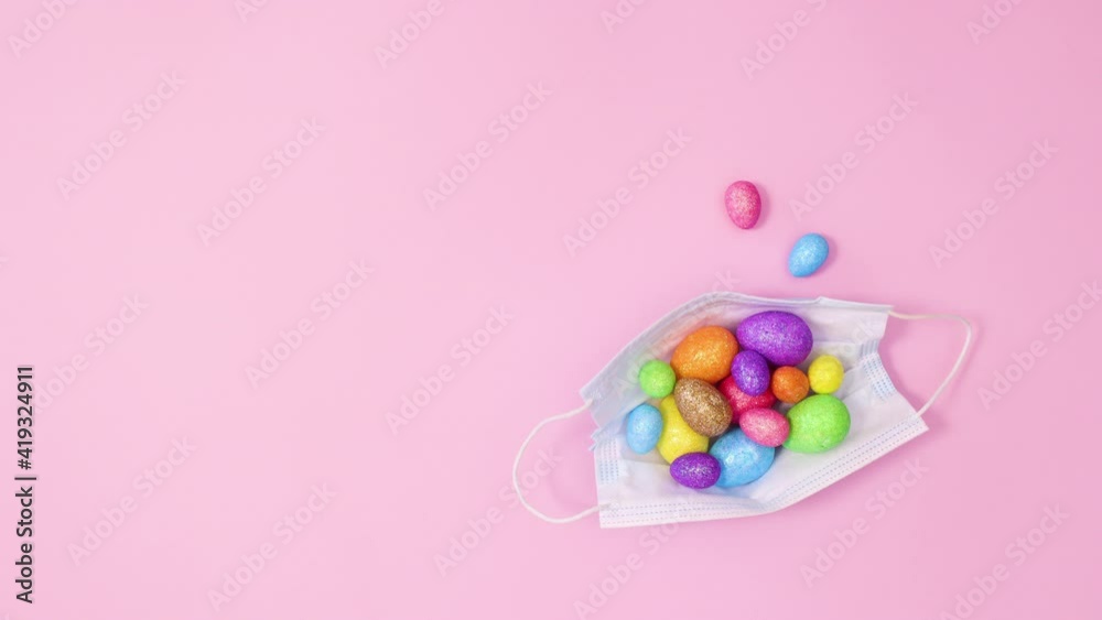 Face mask with Easter vibrant eggs on pastel pink background. Stop motion flat lay Face mask with Easter vibrant eggs on pastel pink background. Stop motion flat lay