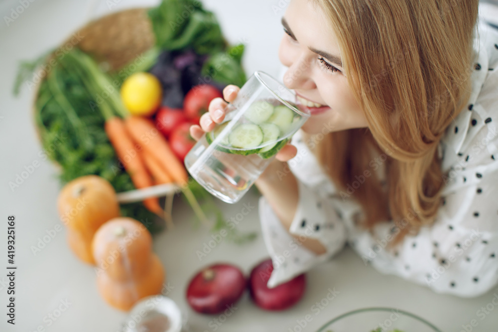 Woman on a diet. Young and happy woman eating healthy salad sitting on the table with green fresh ingredients indoors. High quality photo Woman on a diet. Young and happy woman eating healthy salad sitting on the table with green fresh ingredients indoors. High quality photo