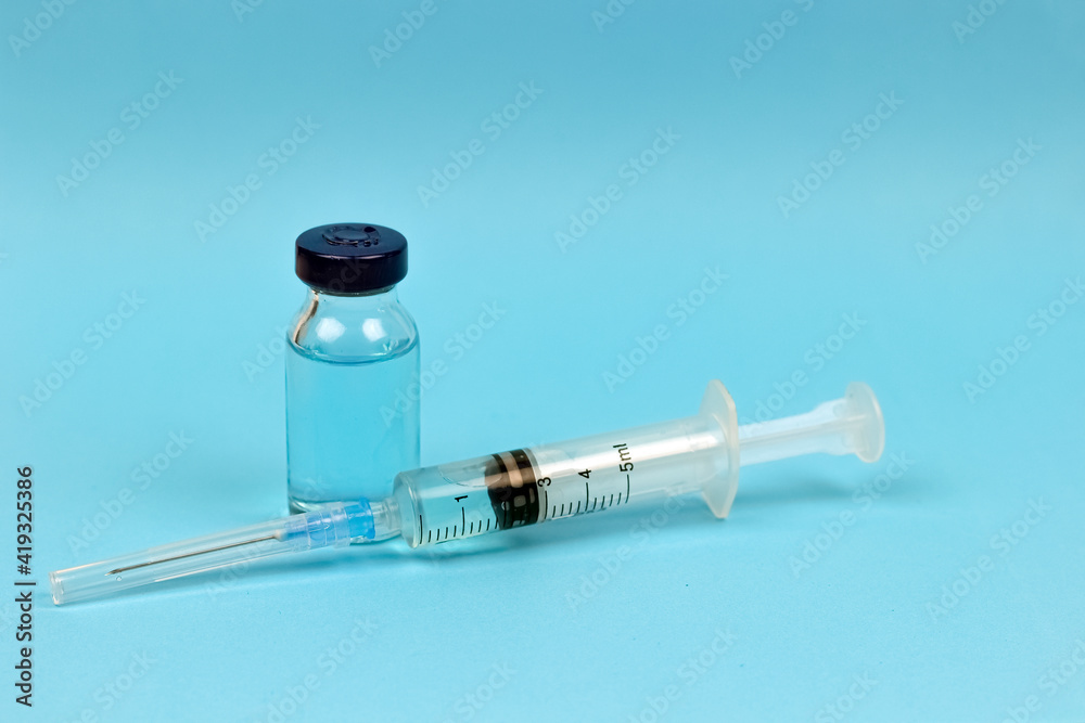 Medical concept - syringe and medical injection vial on blue background Medical concept - syringe and medical injection vial on blue background