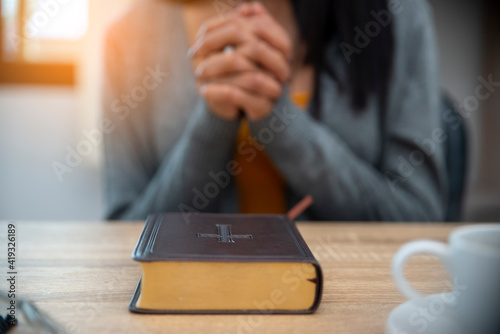 Prayer and bible concept. Hand of Asian female praying, hope for peace and free from coronavirus, Hand in hand together by woman, believes and faith in christian religion at church.