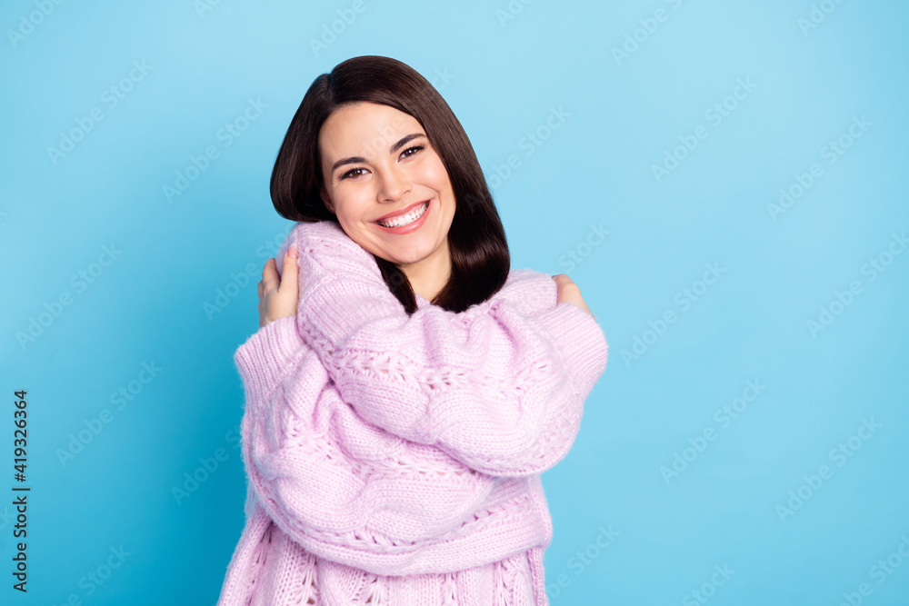 Photo of young cheerful woman happy positive smile embrace herself love comfort isolated over blue color background Photo of young cheerful woman happy positive smile embrace herself love comfort isolated over blue color background