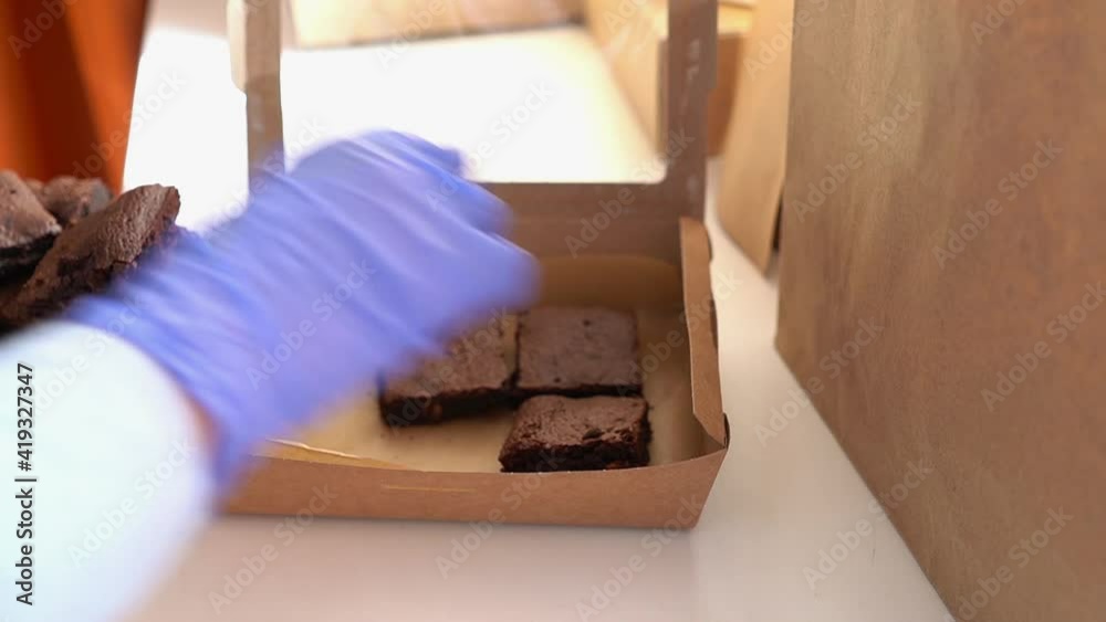Woman putting brownie in box. Homemade pastry delivery. Cake shop business. Woman putting brownie in box. Homemade pastry delivery. Cake shop business.