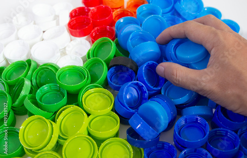 pile of many color recycle plastic bottle caps, recycle plastic bottle in hand