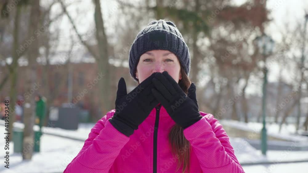 Young woman with braid wearing knitted hat and sports jacket standing in winter park and sending air kiss to camera. Joyful female posing outside. Concept of feeling Young woman with braid wearing knitted hat and sports jacket standing in winter park and sending air kiss to camera. Joyful female posing outside. Concept of feeling