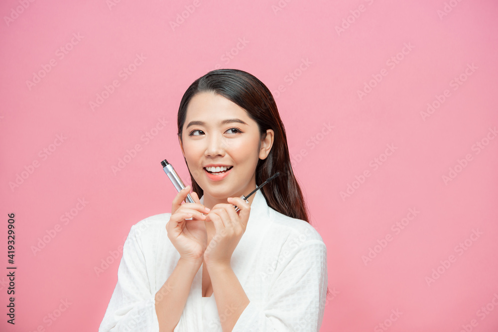 Charming teen girl woman applying mascara / photoset of attractive girl on pink background Charming teen girl woman applying mascara / photoset of attractive girl on pink background