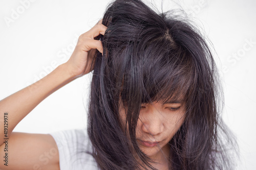 Dandruff on hair of girl. woman is Scratching head because problem rod from fungus on the scalp with messy hair. authentic thailand black hair and skin tan. close up image.