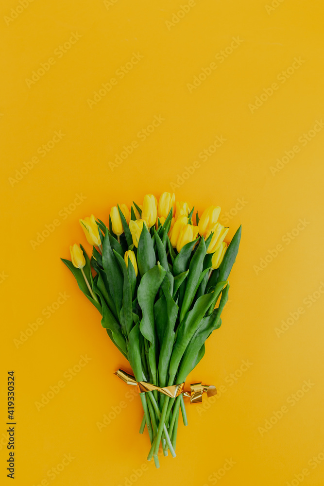 Bright fresh yellow tulips on yellow background. Bunch of yellow tulips on orange background with space for text.