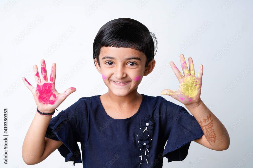 Happy Holi Greeting - Cute little Indian girl with colourful hands, isolated over white background Happy Holi Greeting - Cute little Indian girl with colourful hands, isolated over white background