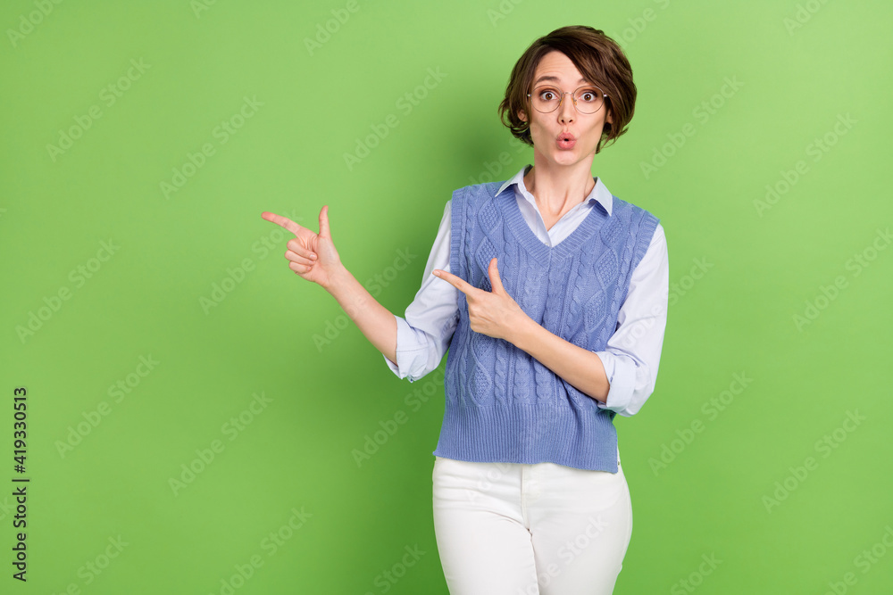 Photo portrait of surprised woman in spectacles pointing empty space staring isolated bright green color background Photo portrait of surprised woman in spectacles pointing empty space staring isolated bright green color background