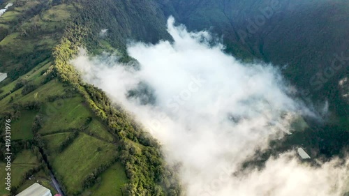 Descending High Elevation Aerials: Patch Of Clouds Clings To A Lush Tree Covered Hill In Sunshine