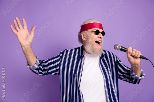 Photo of aged excited man happy positive smile sing song karaoke microphone isolated over violet color background