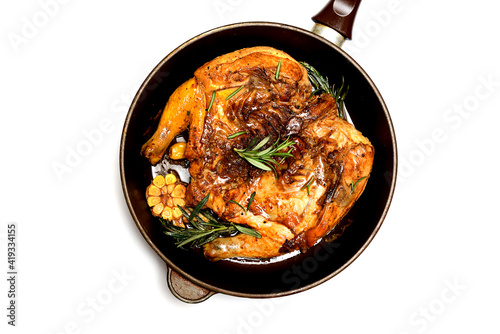 grilled chicken in a frying pan on a white plate with rosemary and garlic