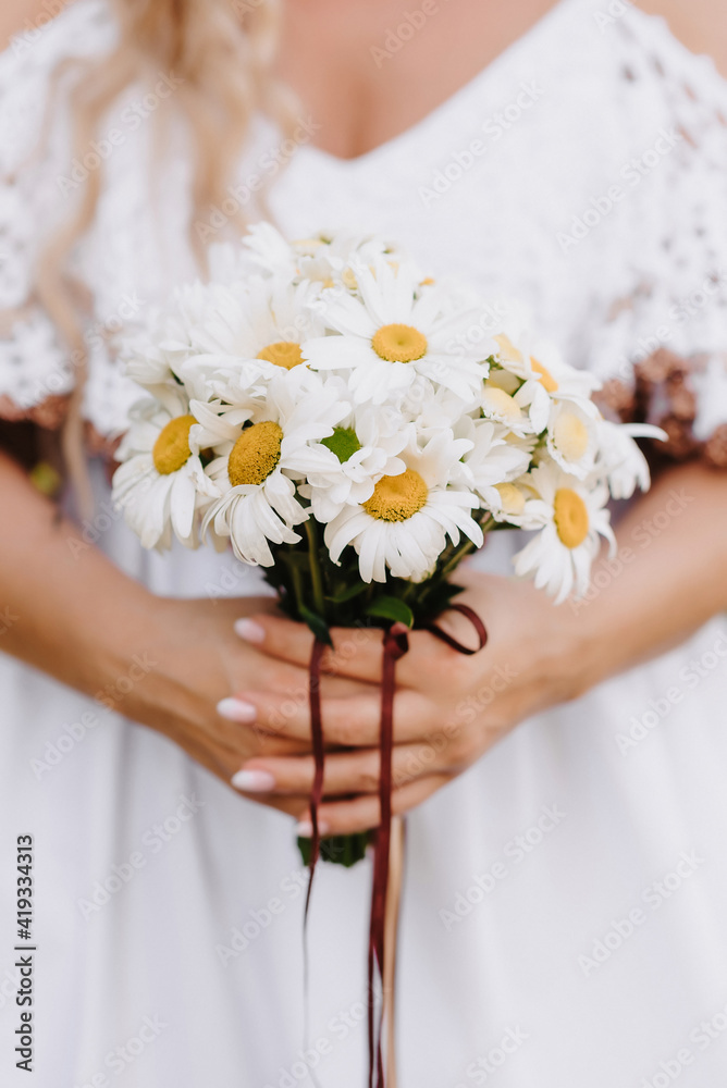 wedding bouquet of daisies in the hands of the bride wedding bouquet of daisies in the hands of the bride