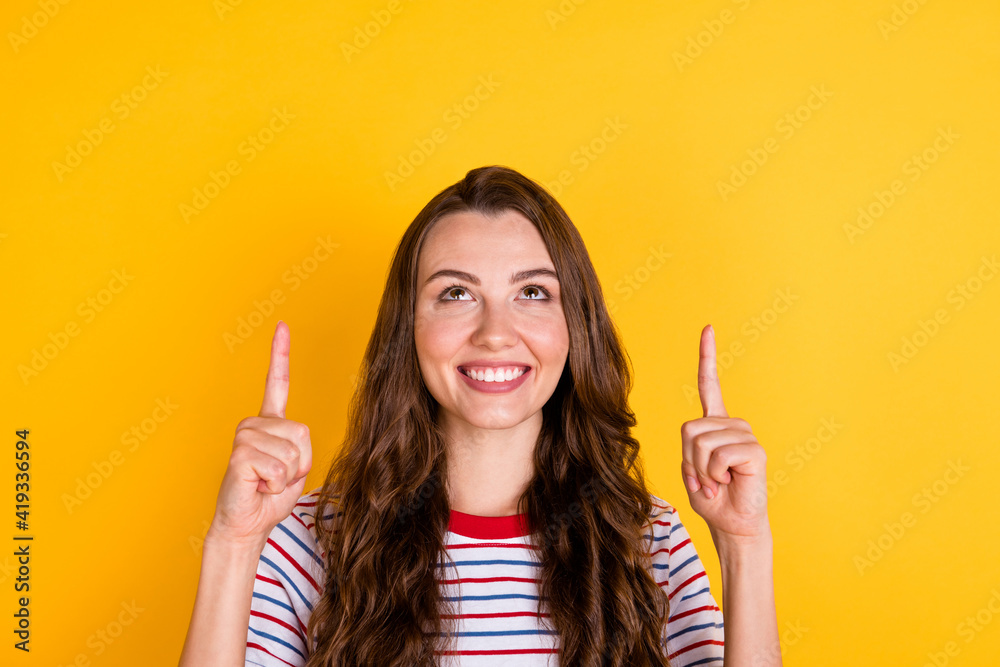 Photo of sweet cute young lady dressed striped t-shirt looking pointing up empty space isolated yellow color background Photo of sweet cute young lady dressed striped t-shirt looking pointing up empty space isolated yellow color background
