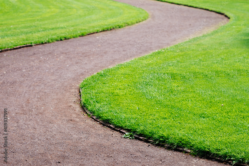 curved footpath in park admist green grass curved footpath in park admist green grass