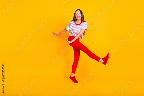 Fototapeta Naklejka Na Ścianę i Meble -  Photo of carefree lady dance have fun wear striped shirt red trousers sneakers isolated yellow color background