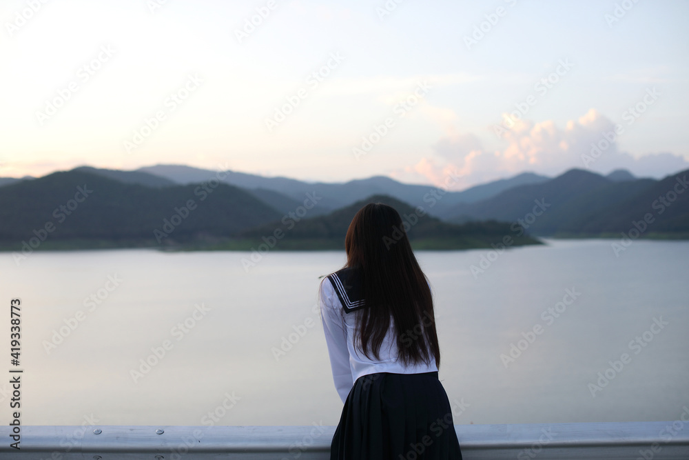 Asian school girl looking mountain with river in sunrise