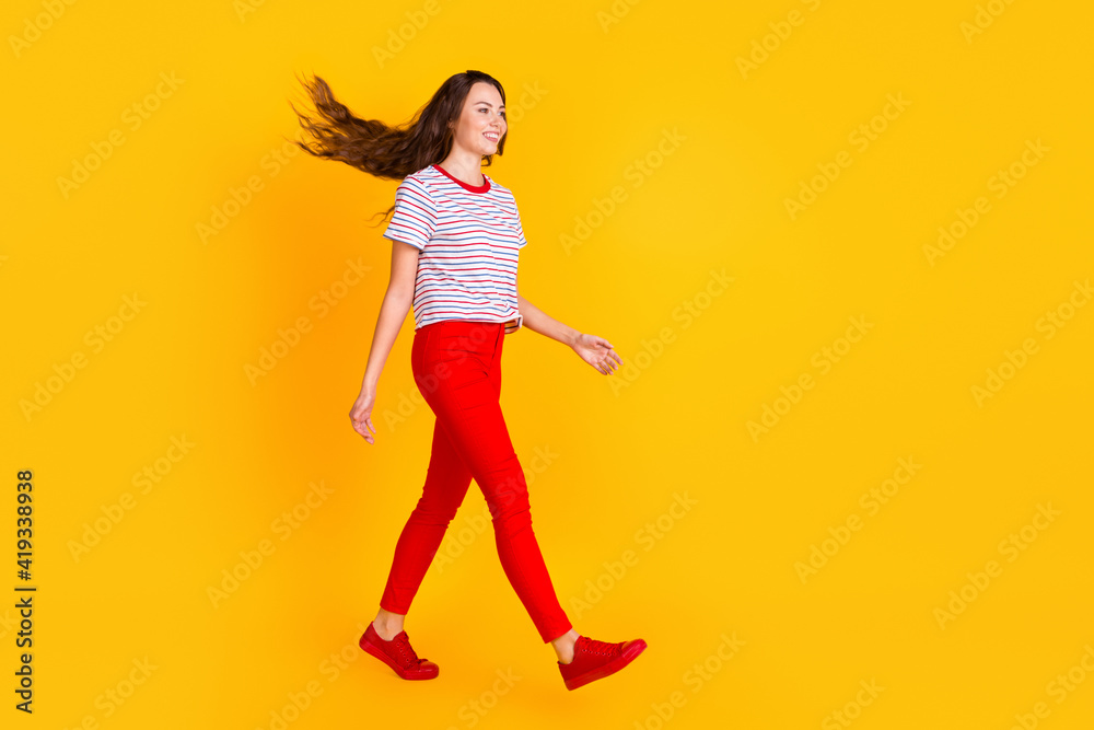 Full size profile side photo of young attractive girl happy positive smile go walk isolated over yellow color background Full size profile side photo of young attractive girl happy positive smile go walk isolated over yellow color background