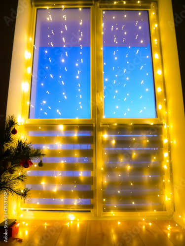 Beautiful blurred flickering yellow light. Home decoration with garlands on the window  night Bokeh lighting. Festive background.