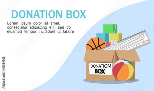 Cardboard donation box full of toys, books, clothes and devices. Volunteer giving clothing donation box