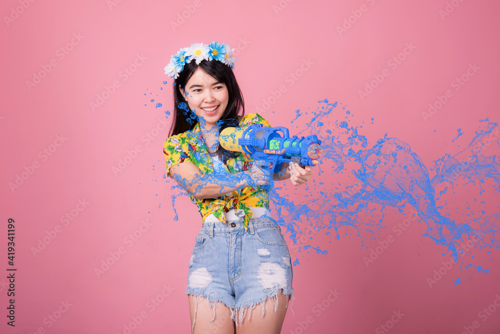 Young happy beauty Asian woman holding plastic water gun at Songkran festival, Thailand. Thai New Year's Day. Isolated on black background. Young happy beauty Asian woman holding plastic water gun at Songkran festival, Thailand. Thai New Year's Day. Isolated on black background.