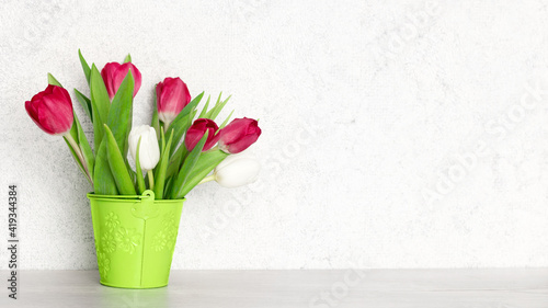 Fototapeta Naklejka Na Ścianę i Meble -  Light spring widescreen background. Red and white tulip flower bouquet on the table near the wall with copy space